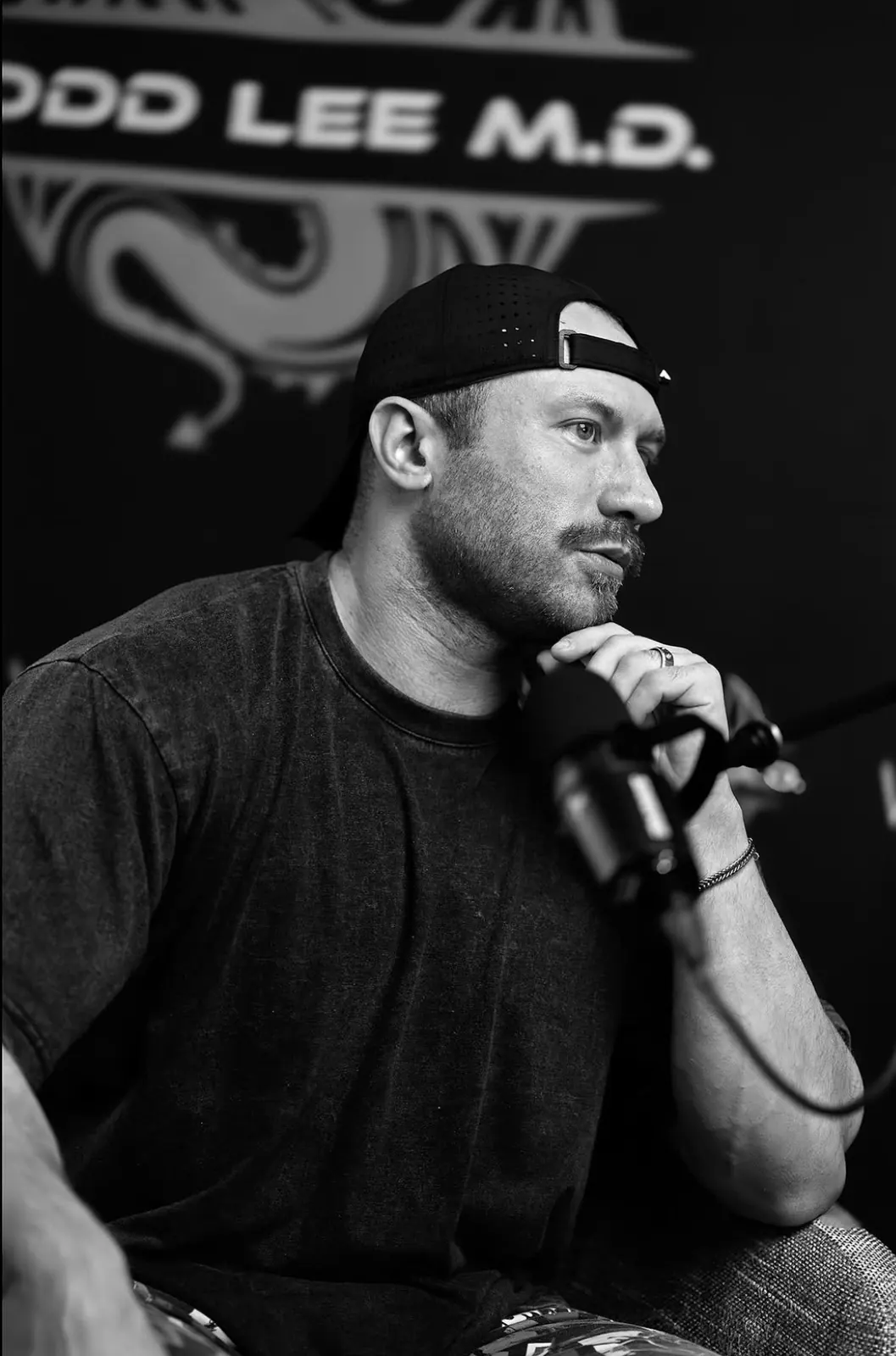 David DeMesquita speaking on a podcast, black and white