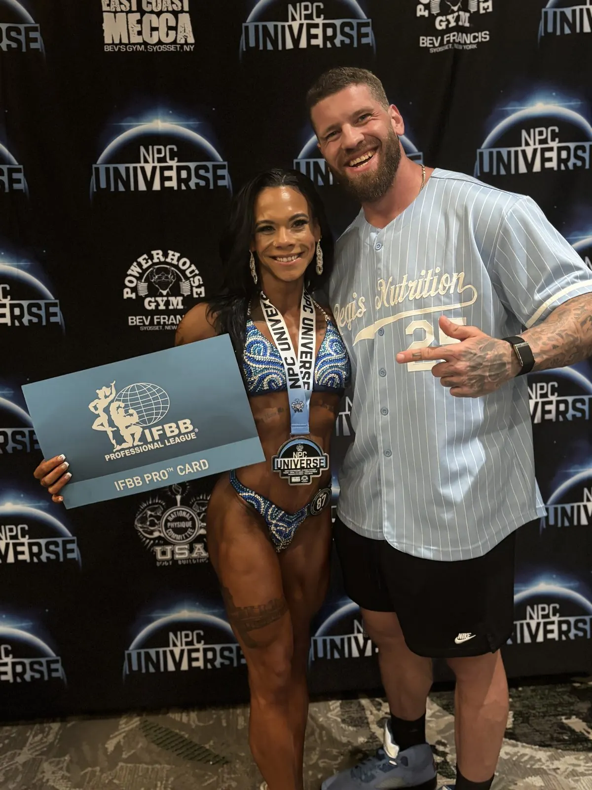 Kyle Gabriel with his athlete holding her IFBB Pro card