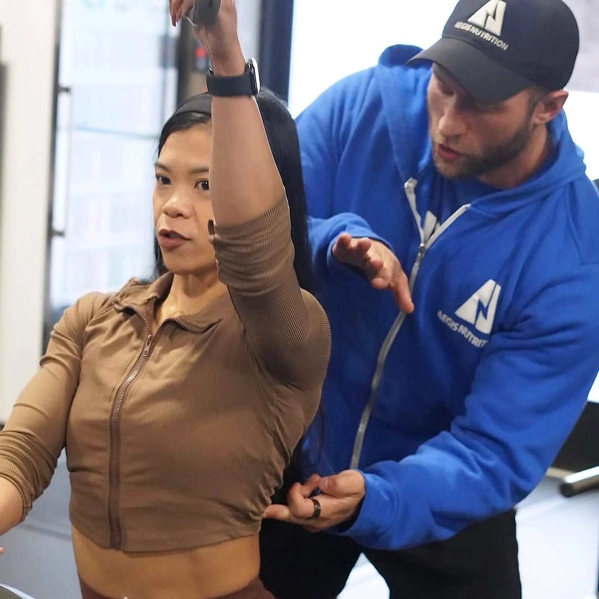 An Aegis coach adjusting a client’s arm position
